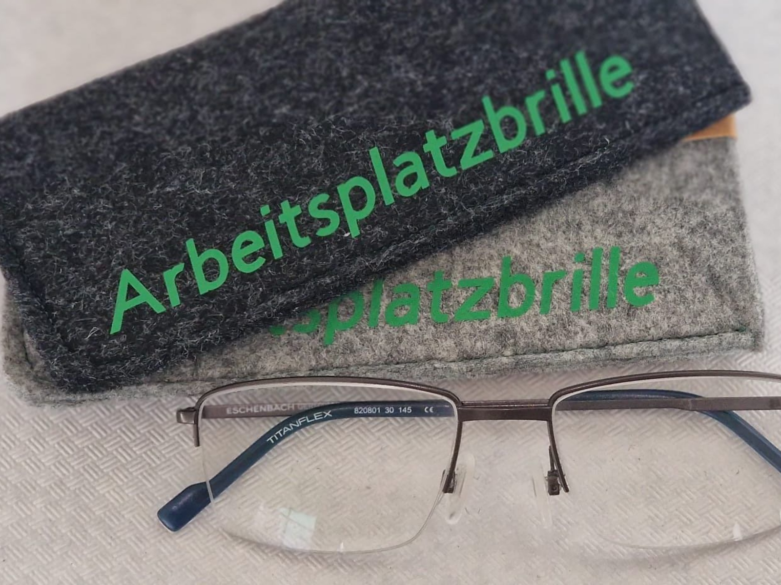 Brille und Etui mit der Aufschrift „Arbeitsplatzbrille“ in Grün.