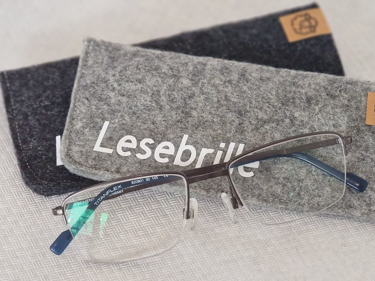 Brillen mit grauen Etuis; auf einem Etui ist „Lesebrille“ aufgedruckt.