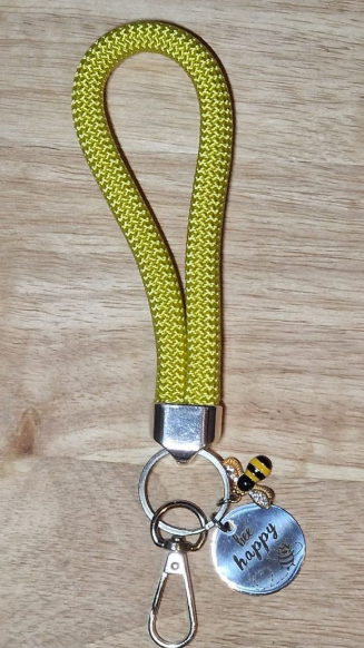 Gelber Schlüsselring mit Bienenanhänger und dem Slogan „Bee happy“.