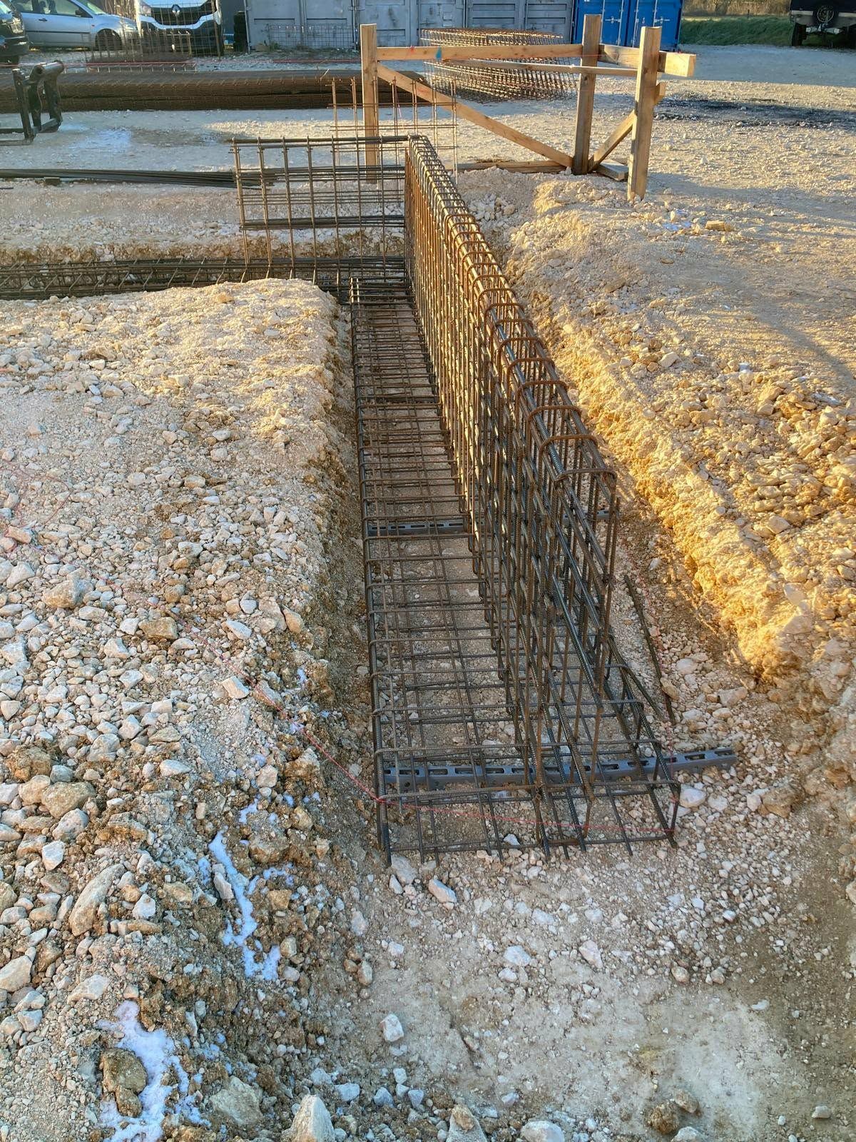 Stahlbewehrungskorb für einen Fundamentgraben auf einer Kiesbaustelle.