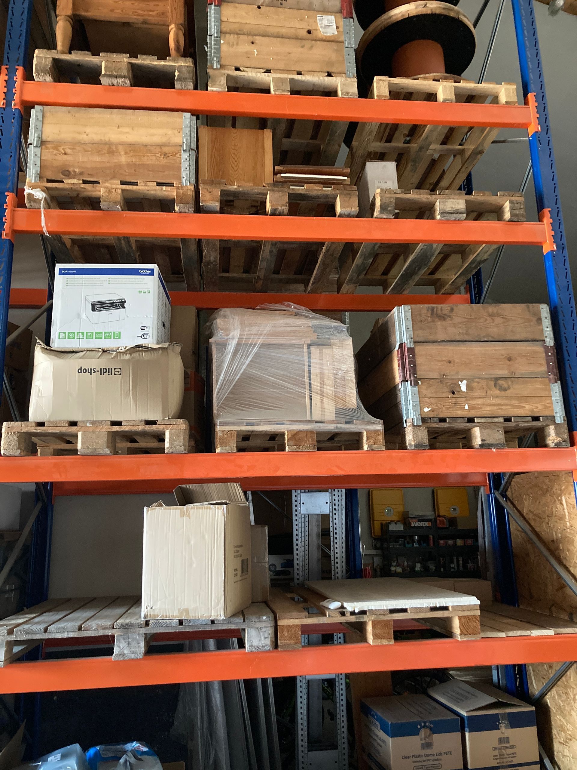 Mehrstöckiges Industrieregal mit orangefarbenen Trägern, an denen verschiedene Holzpaletten, Kisten und Kartons befestigt sind.
Privatarchiv Martin Heinze