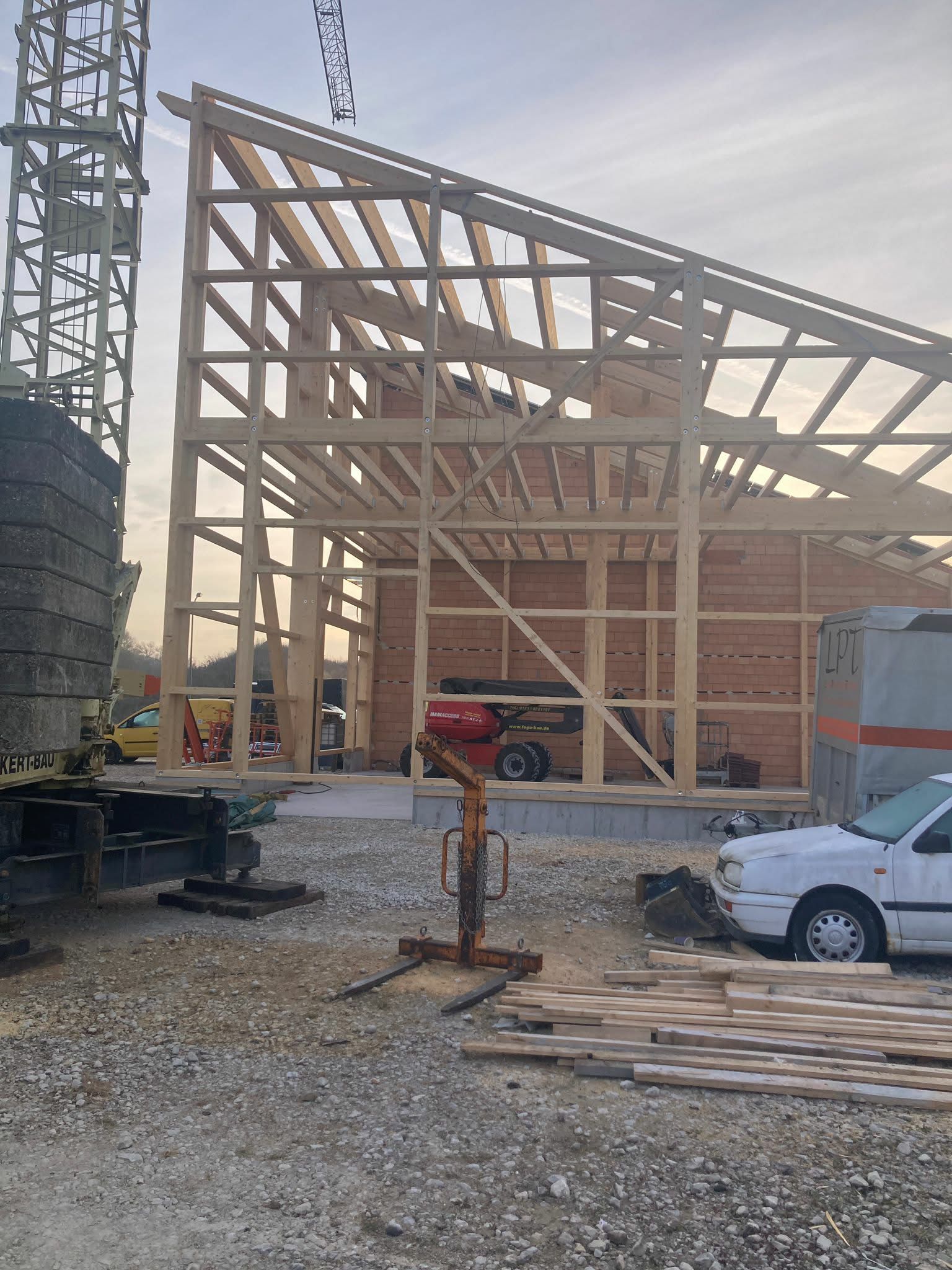 Auf einer Baustelle ist ein großes, im Bau befindliches Fachwerkgebäude zu sehen; in der Nähe stehen ein Kran und ein Auto geparkt.
Privatarchiv Martin Heinze