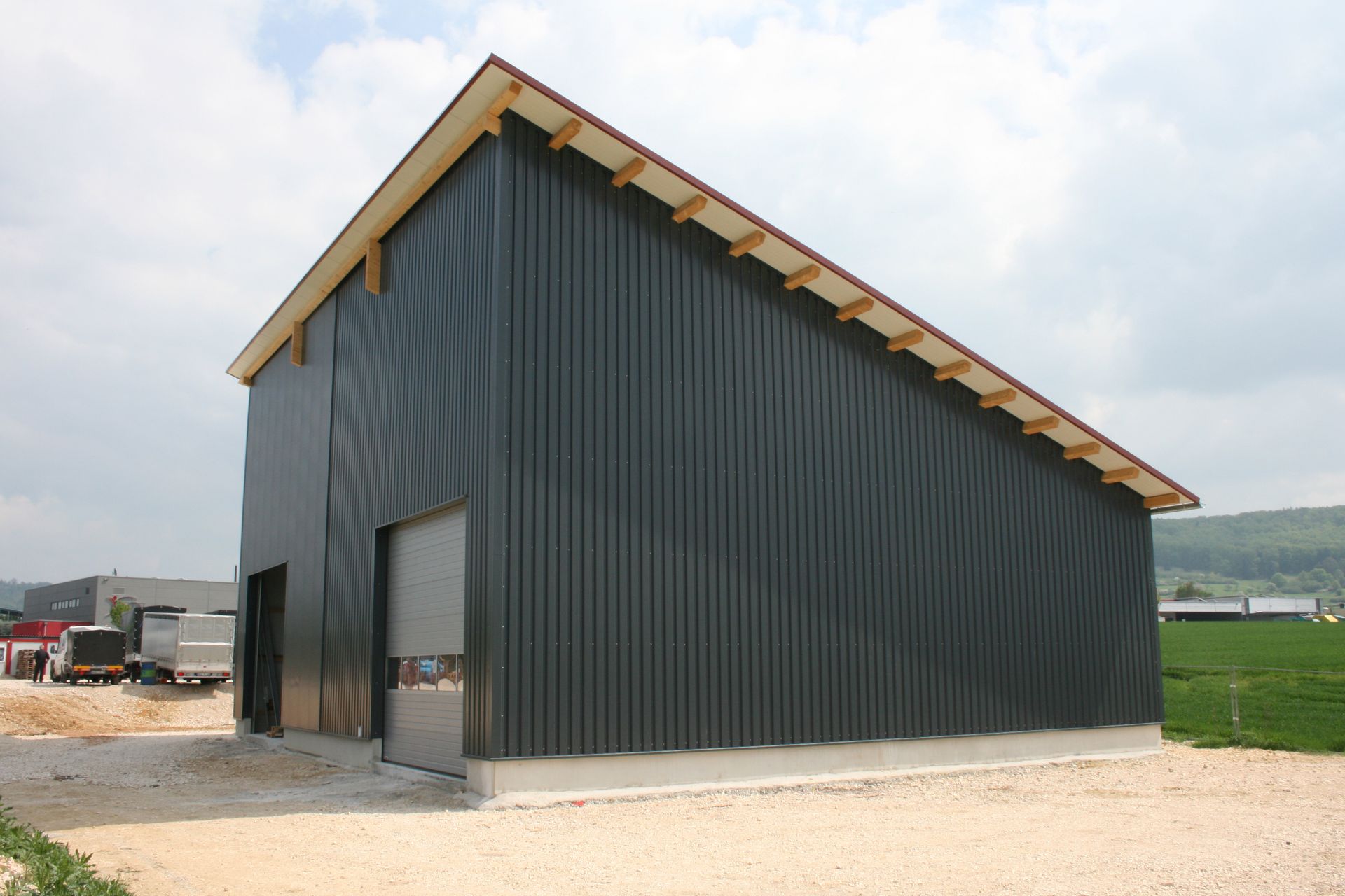 Ein modernes, dunkelgraues Industriegebäude mit schrägem Dach und Rolltor auf einem Kiesplatz unter bewölktem Himmel.
Privatarchiv Martin Heinze