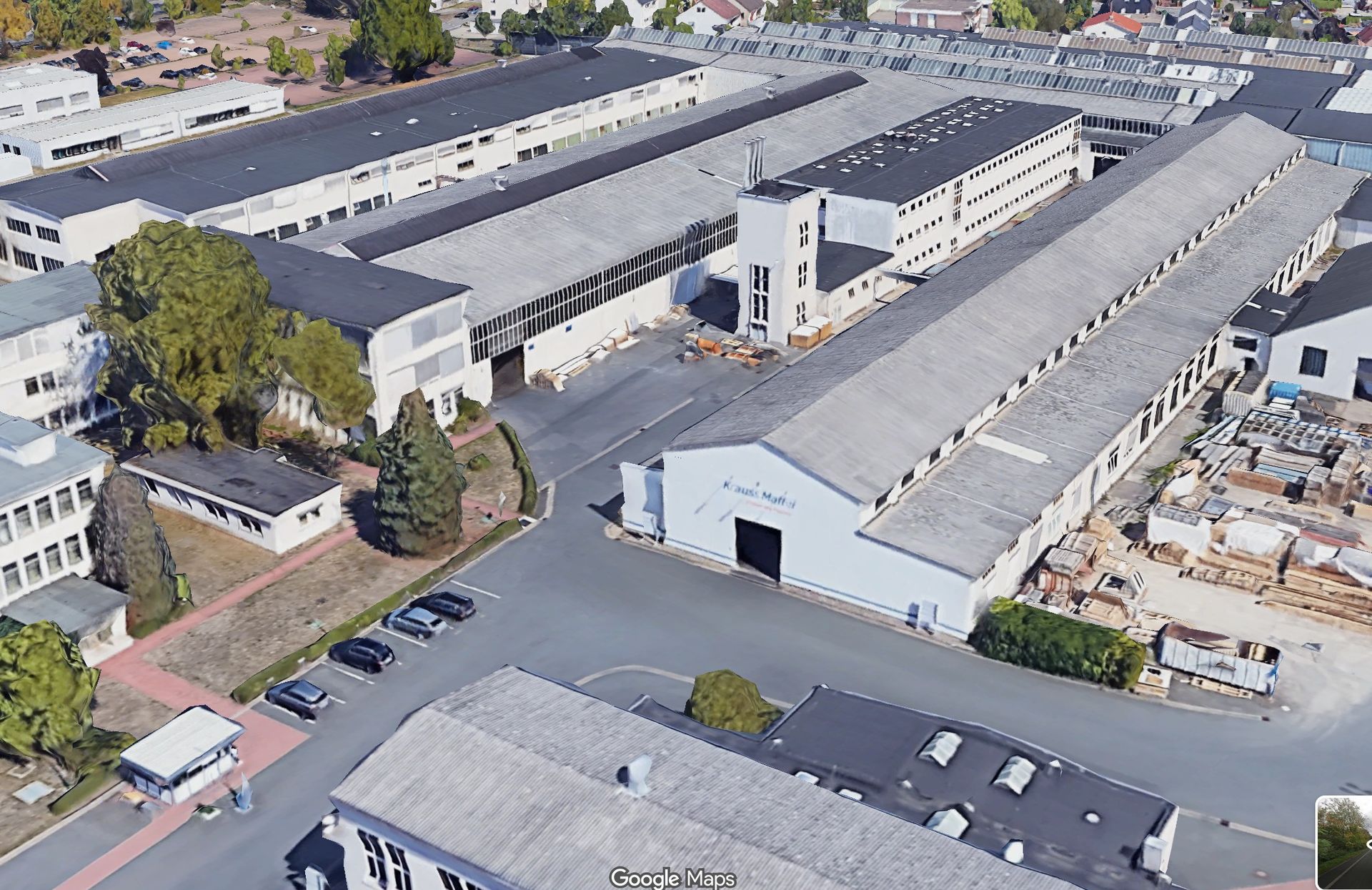 Luftaufnahme eines Industriekomplexes mit langen, weißen Lagerhallen und Parkplätzen.