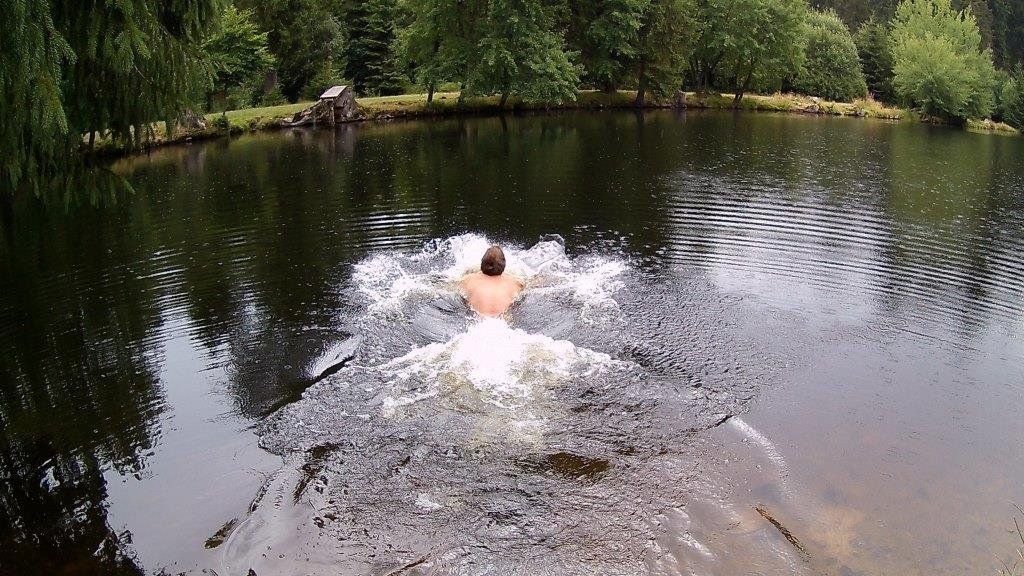 Ein Mann schwimmt in einem Badesee in Deutschland im Regen