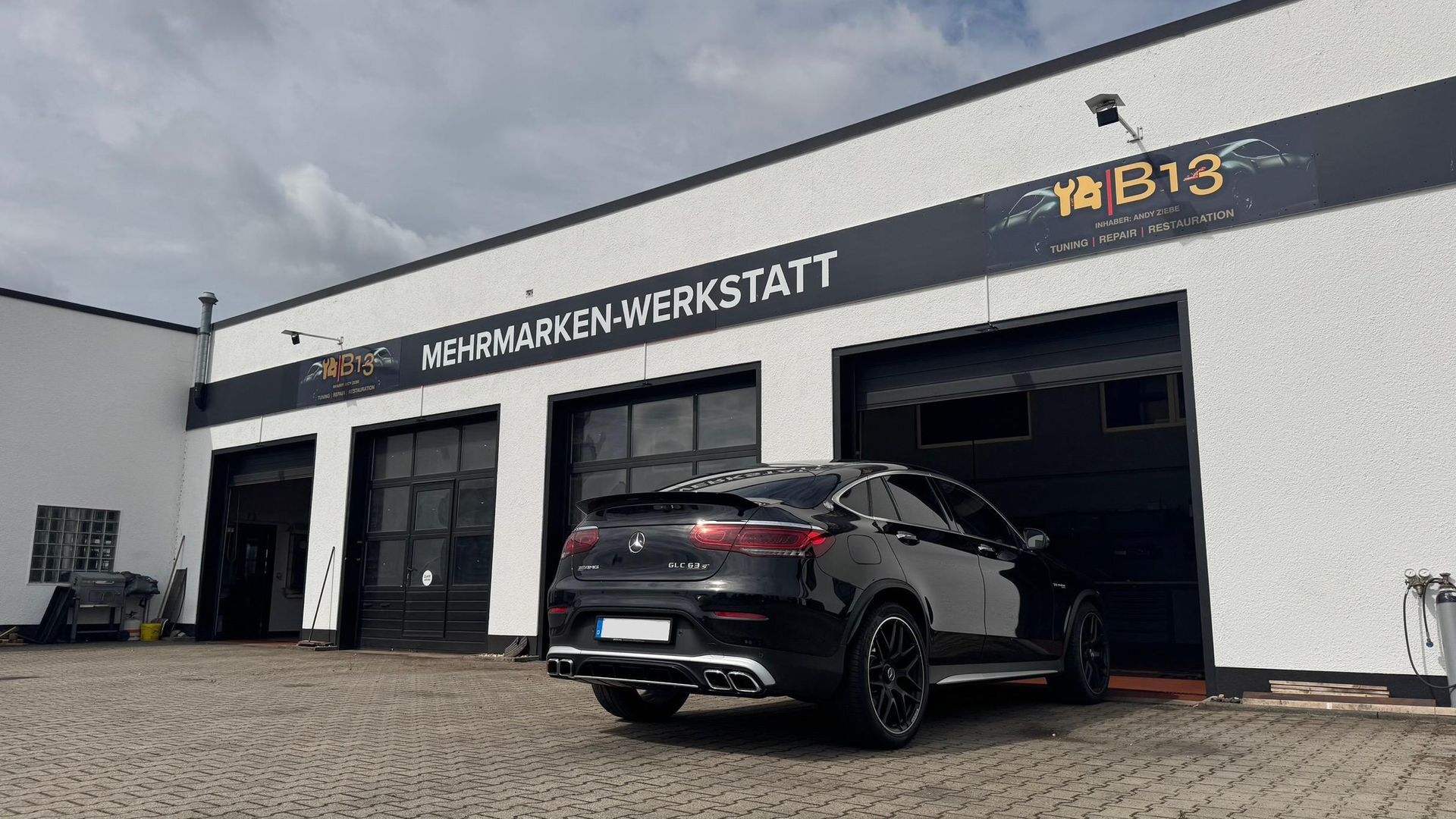 Außenansicht der B13 Kfz-Werkstatt in der Roßlauer Straße 102, Dessau-Roßlau, moderne Werkstatthalle mit Parkplätzen.