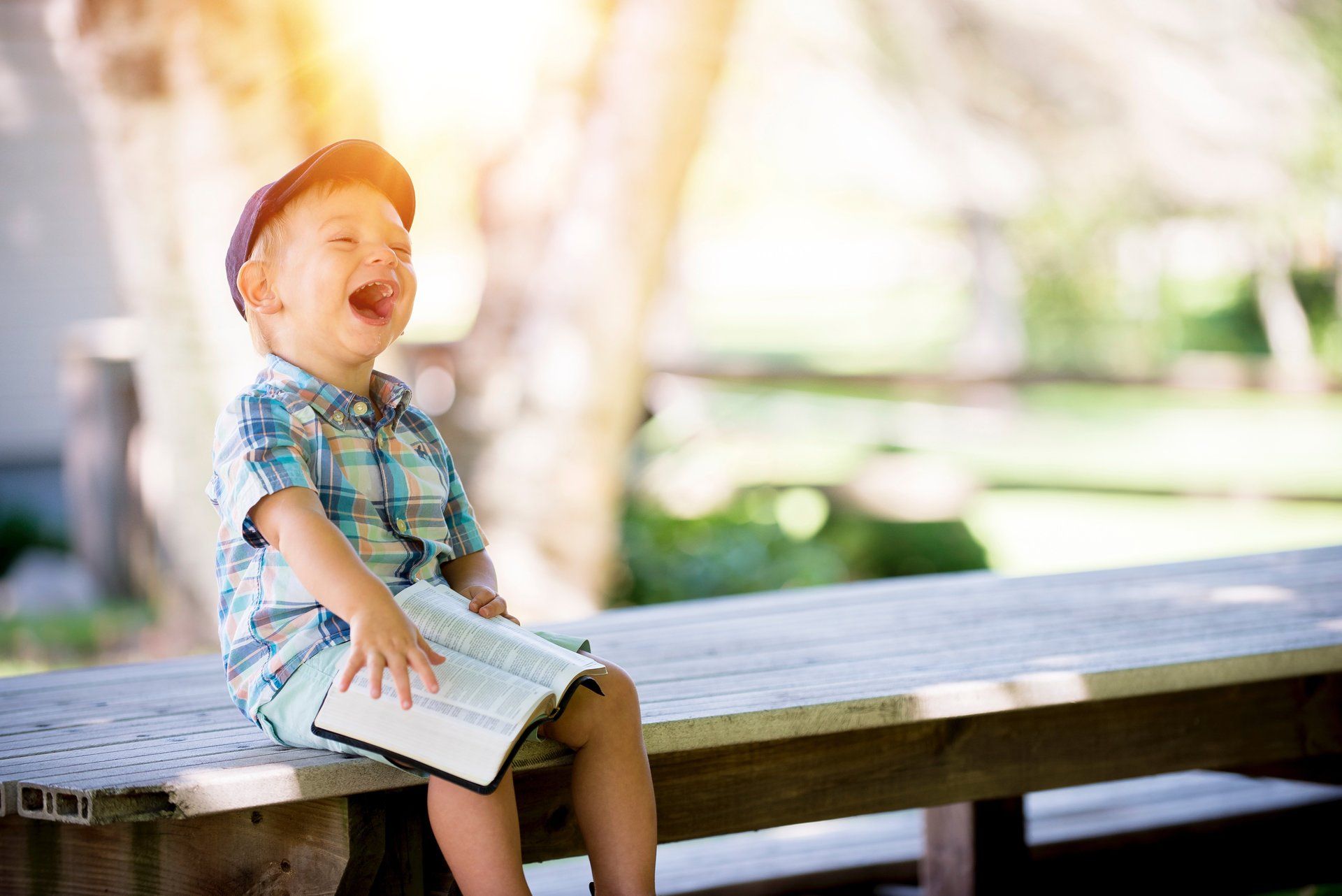 Laughing child with book on bench. Credit: Ben White at Unsplash.