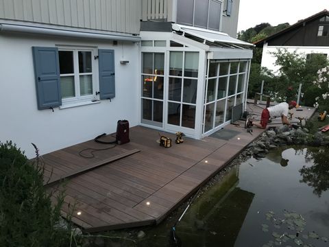 Schwimmteich Steg Veranda aus WPC Megawood Signum Muskat mit Terrassenbeleuchtung und integrierten Granitplatten für Feuerstellen