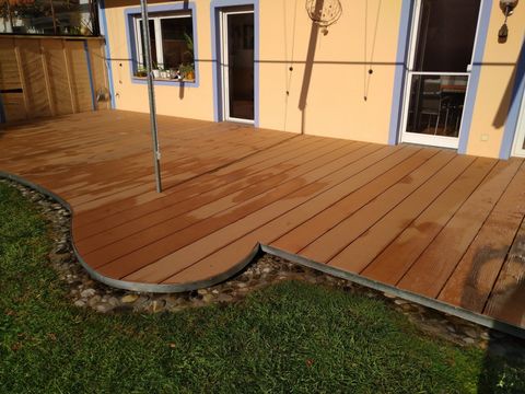 Grosse Gartenterrasse in WPC Megawood Jumbo Premium naturbraun, mit Metallkante zum Rasen.