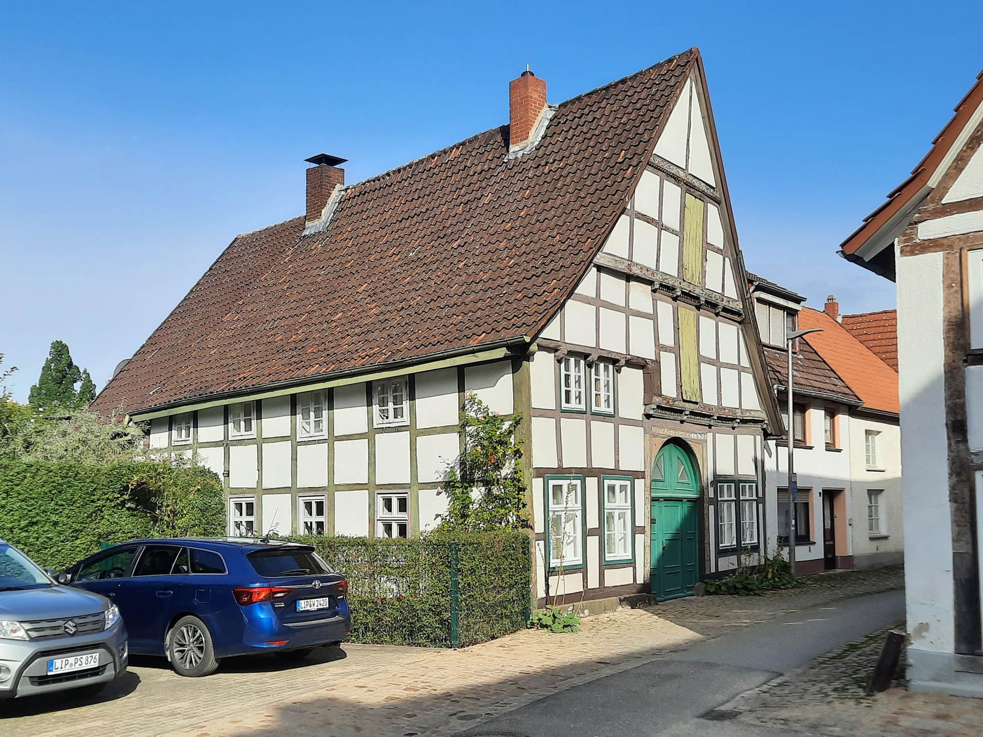 Schrägansicht eines zweigeschossigen Fachwerkhauses mit Satteldach. Im Giebel ein Torbogen und darüber Türen zum Speichern.