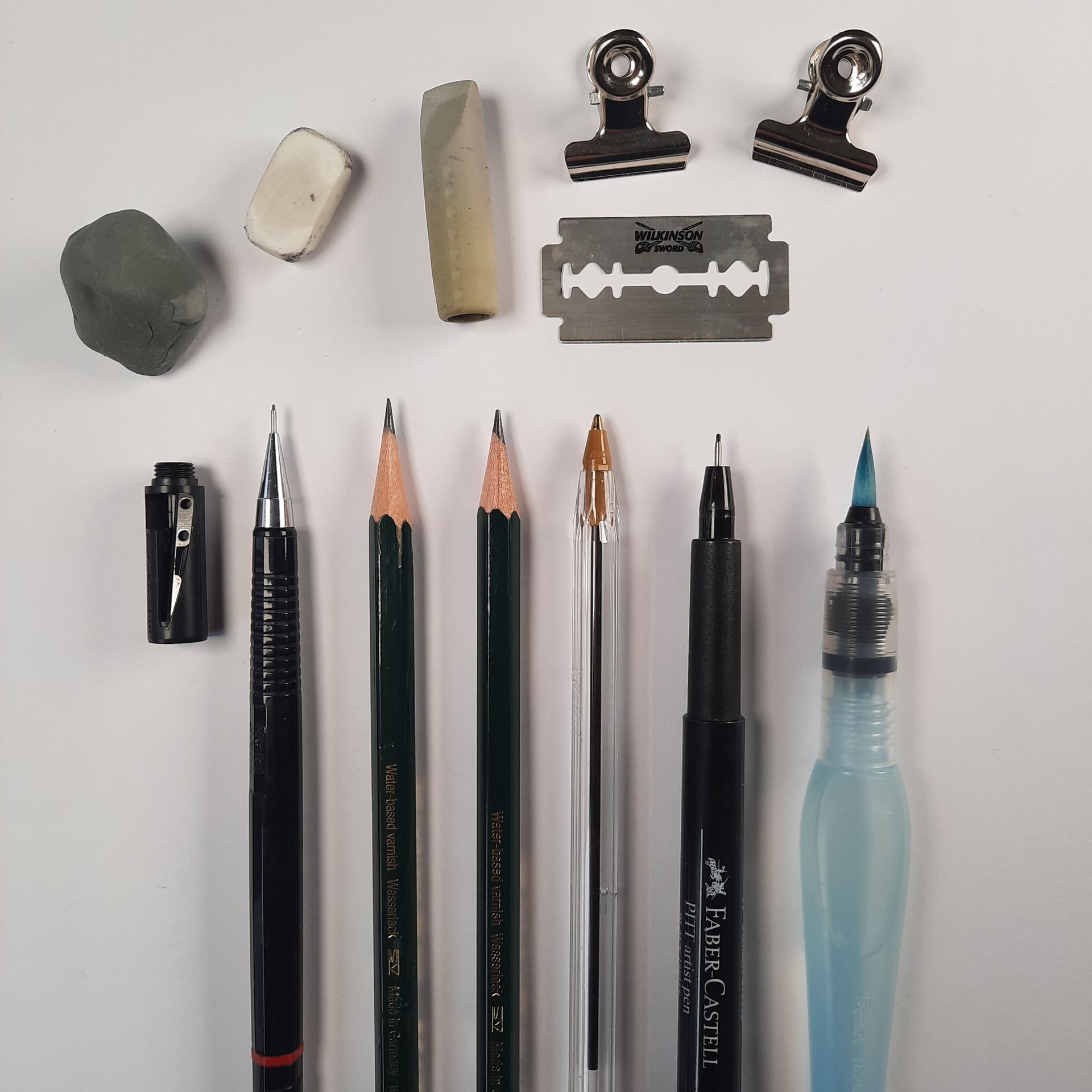 Zeichenmaterialien: Bleistifte, Kuli, Filzstift, Wassertankpinsel. Metallklammern, Radiergummi und Rasierklinge.