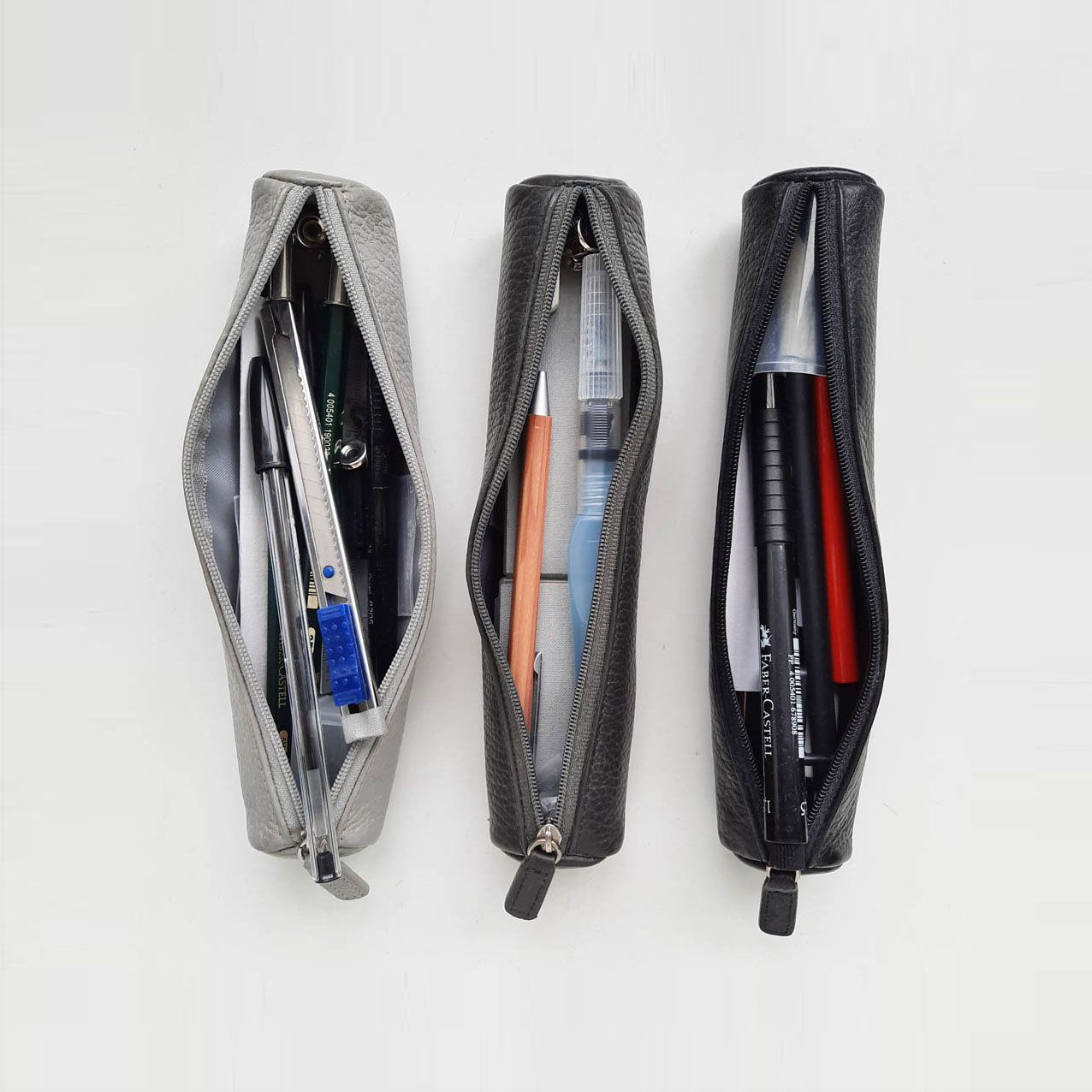 Drei geöffnete Ledermappen mit Stiften.
