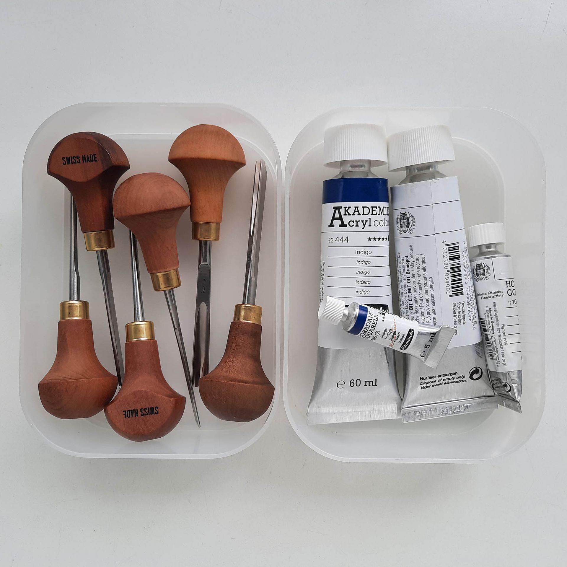 Zwei Schalen mit Linolschnitt-Werkzeug und Tuben mit Farbe.