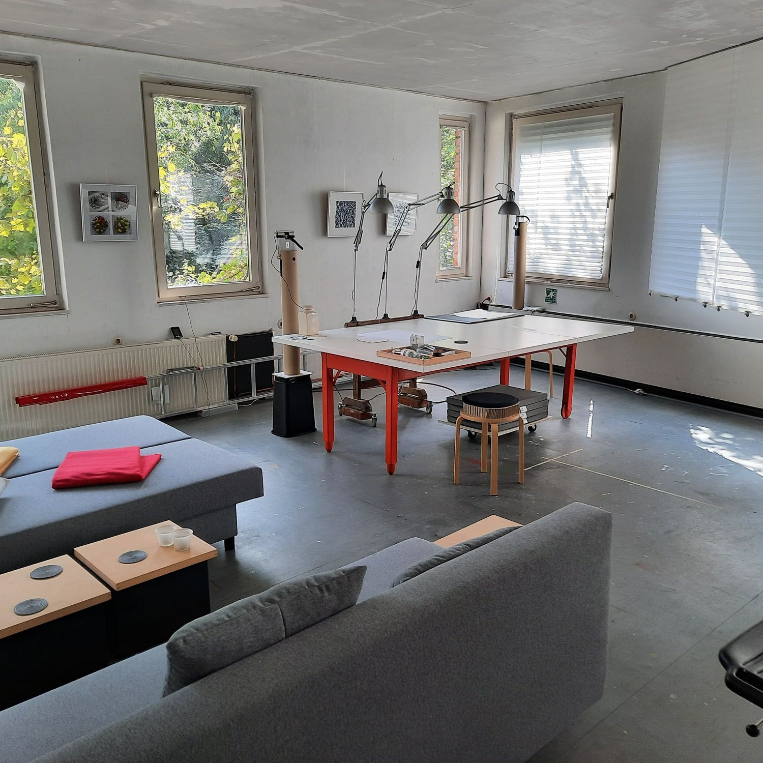 Blick ins Atelier mit großem Tisch und im Vordergrund mit einem Sofa.
