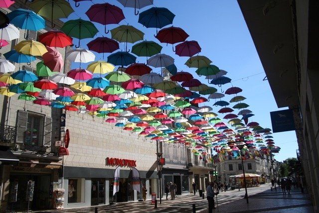 Hundreds of open multi-coloured umbrellas hanging overhead Samur France