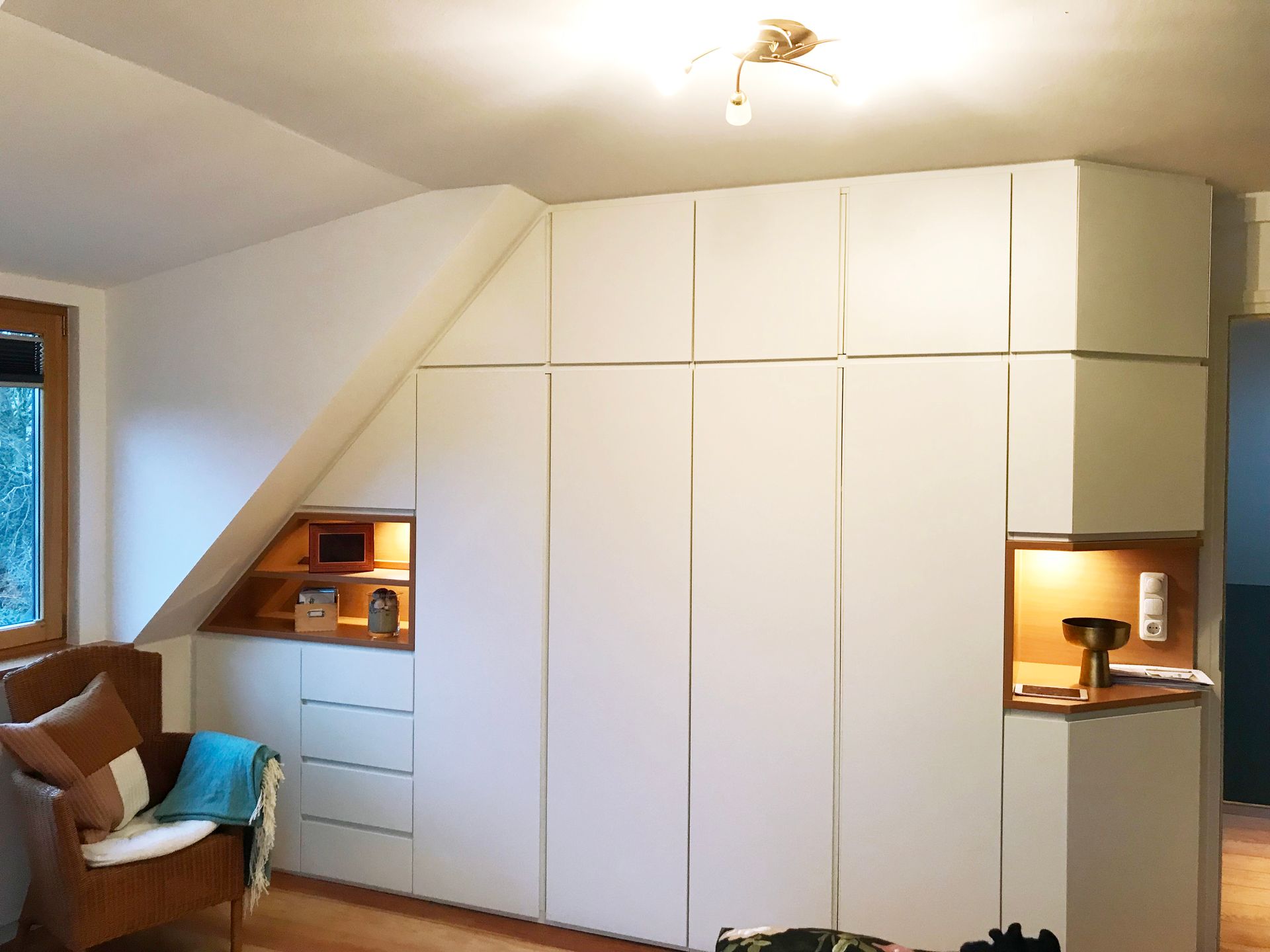 weißer Einbauschrank unter Dachschräge, integrierte Holzregale mit indirekter Beleuchtung, Schrankwand, Stauraum