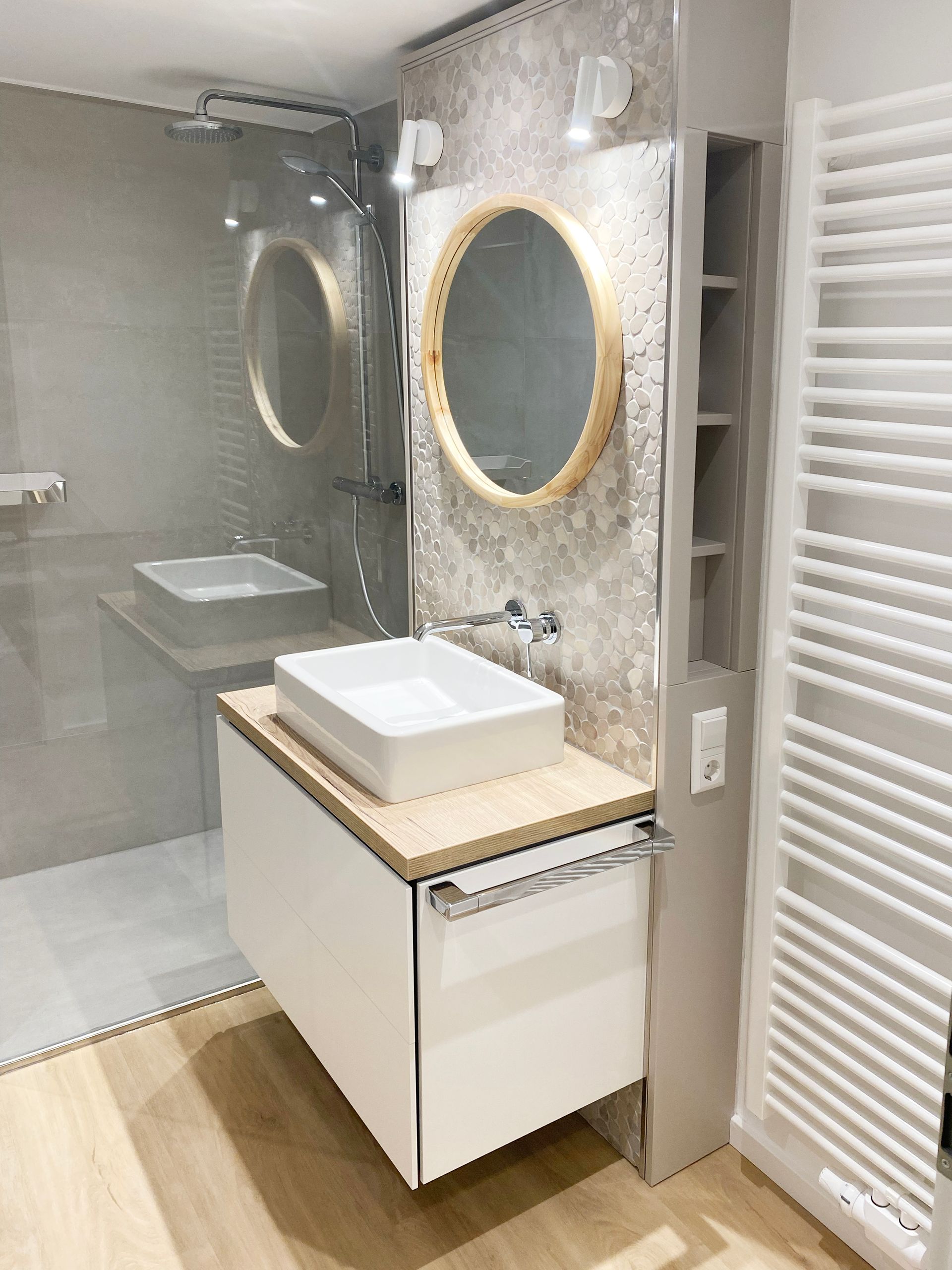 Badezimmer mit Aufsatzwaschbecken, schwebendem Waschtisch, bodenebener Dusche und grauen Fliesen.