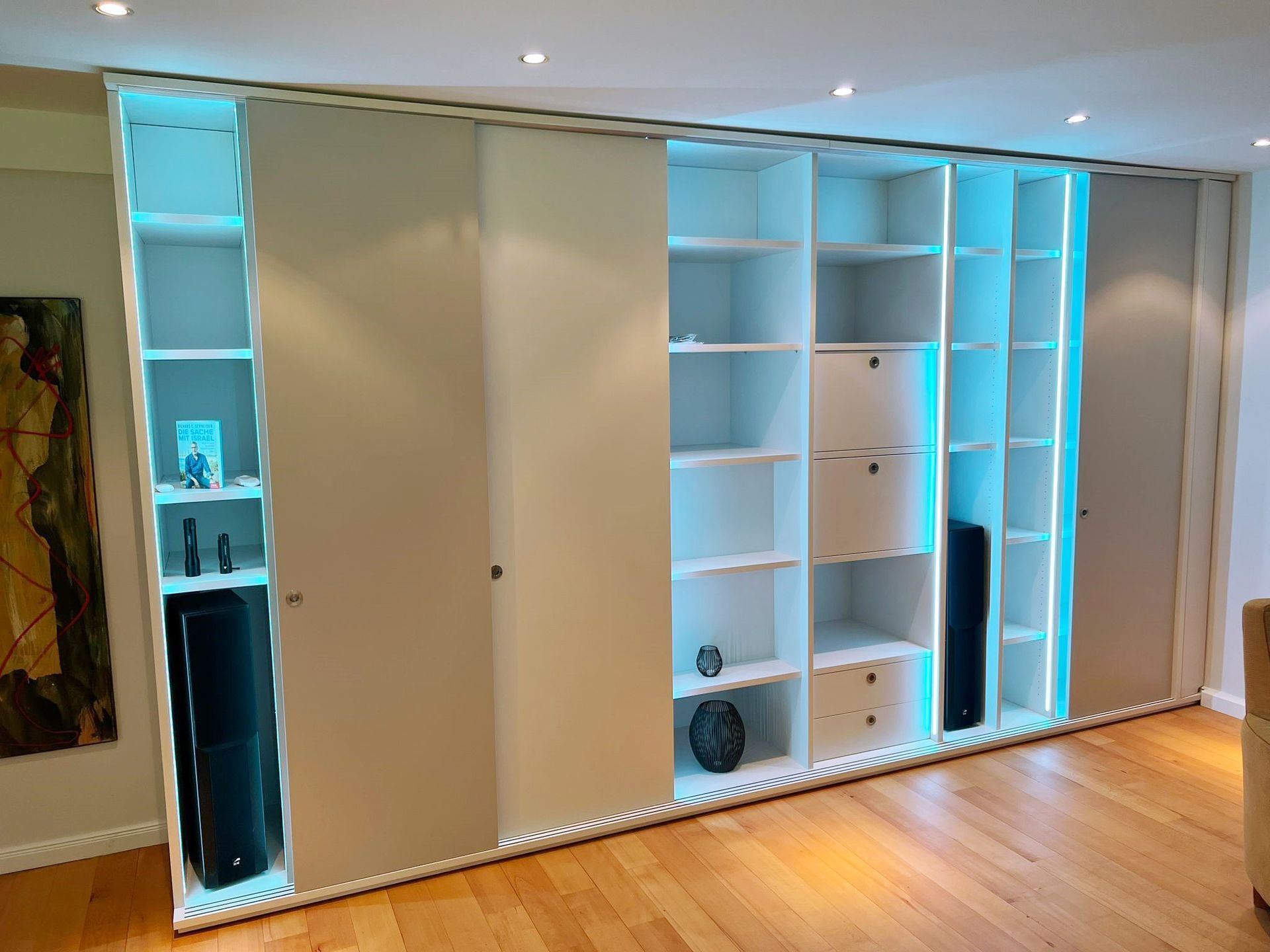 Wohnzimmer mit maßgeschneidertem Einbauschrank, LED-Beleuchtung, Schiebetüren und Schubfächern für individuelle Atmosphäre.