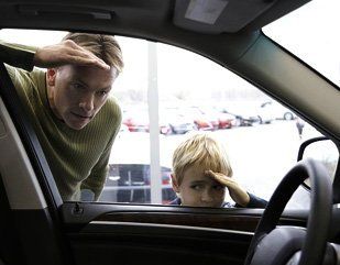 Man and child looking through front window of car