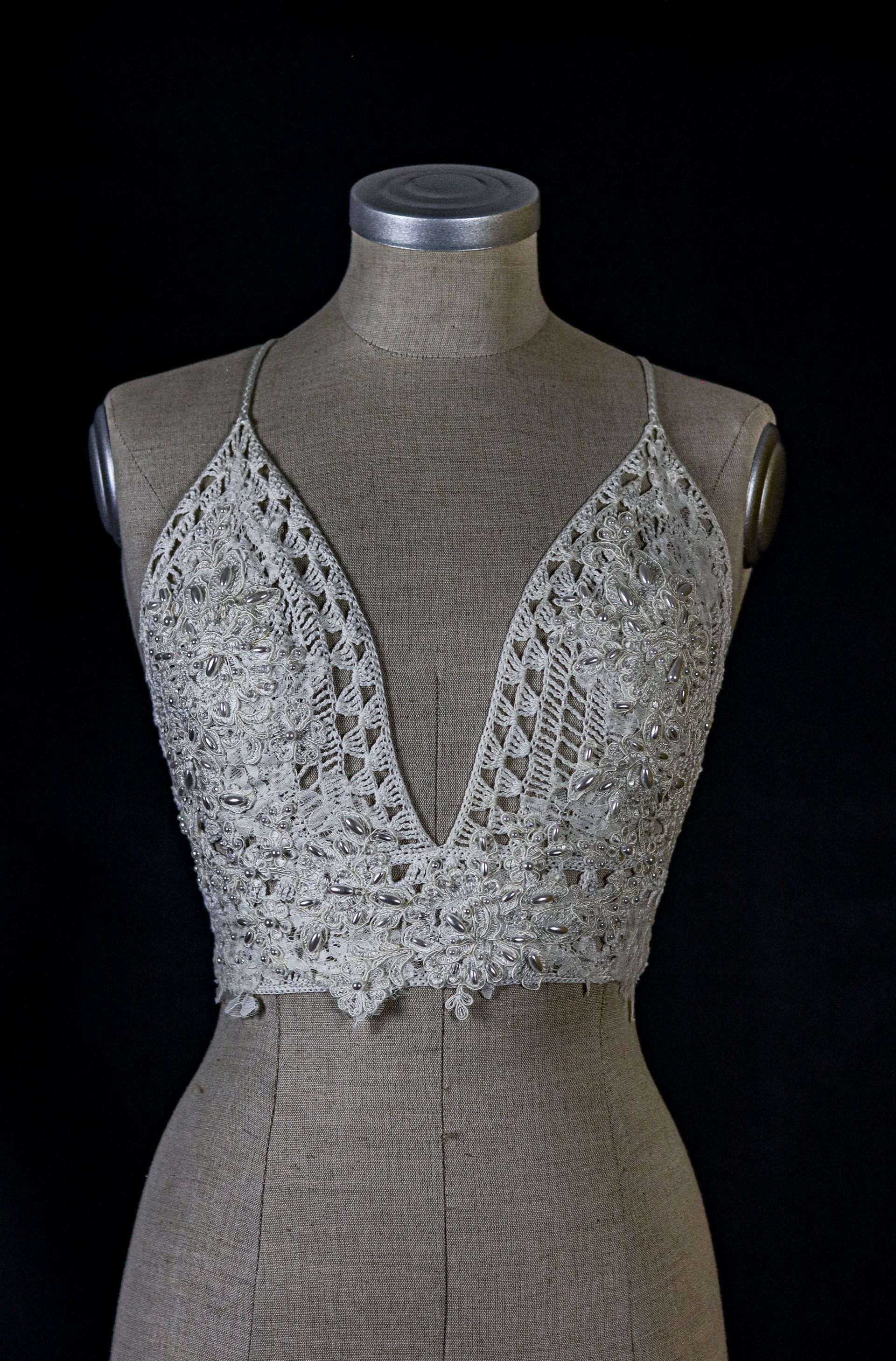 Handgefertigtes Häkeloberteil von Katyliz auf einer Büste – unkonventionelle Brautmode mit feiner Spitze und Perlen-Details