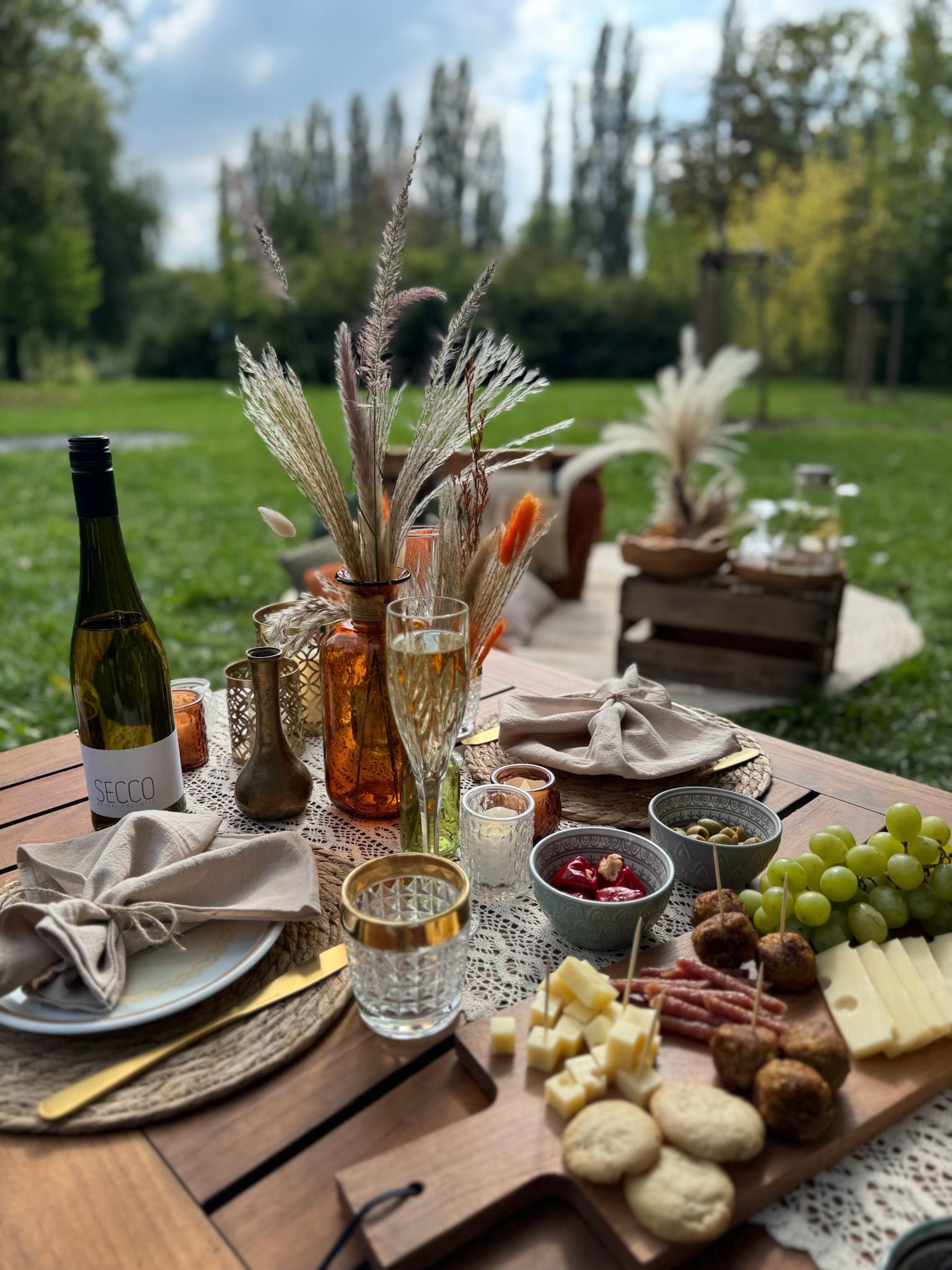 Picknicktisch-Set für ein Treffen im Freien, mit Speisen, Getränken und dekorativen Elementen.