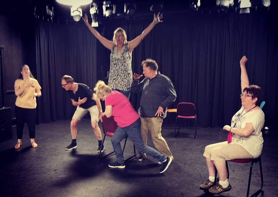 Movement workshop people with arms out, on different levels, making gestures inspired by witchcraft