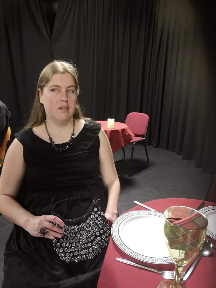 Alex wearing black dress and holding silver glittery purse.