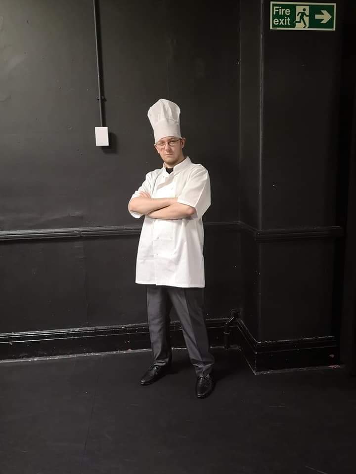 Anthony folding arms wearing chef outfit with serious look on face