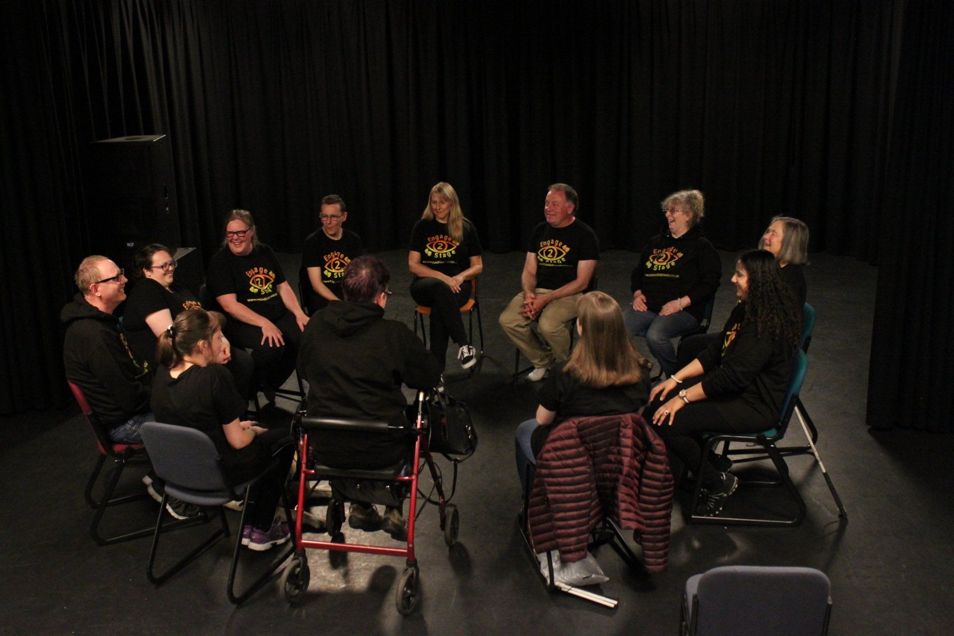 Group in black box studio sat in circle
