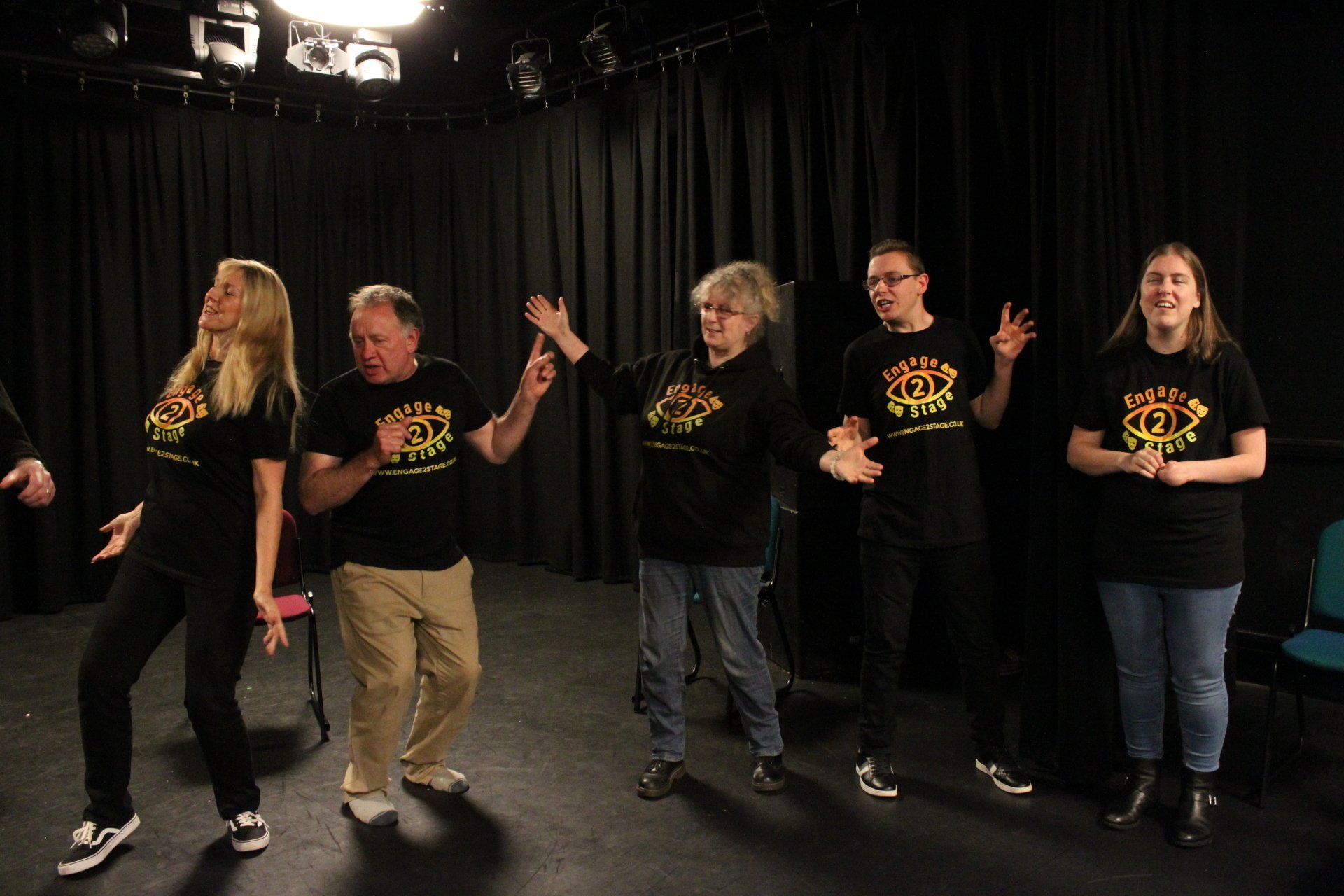 Group in black box studio stood in line making gestures