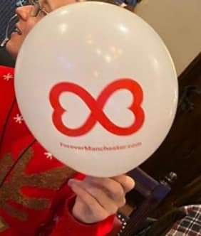Holding balloon featuring forever Manchester logo