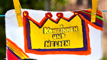 Ein buntes Protestbanner mit der Aufschrift „Konsinnen und Helden“ ist an einer Wäscheleine befestigt.
