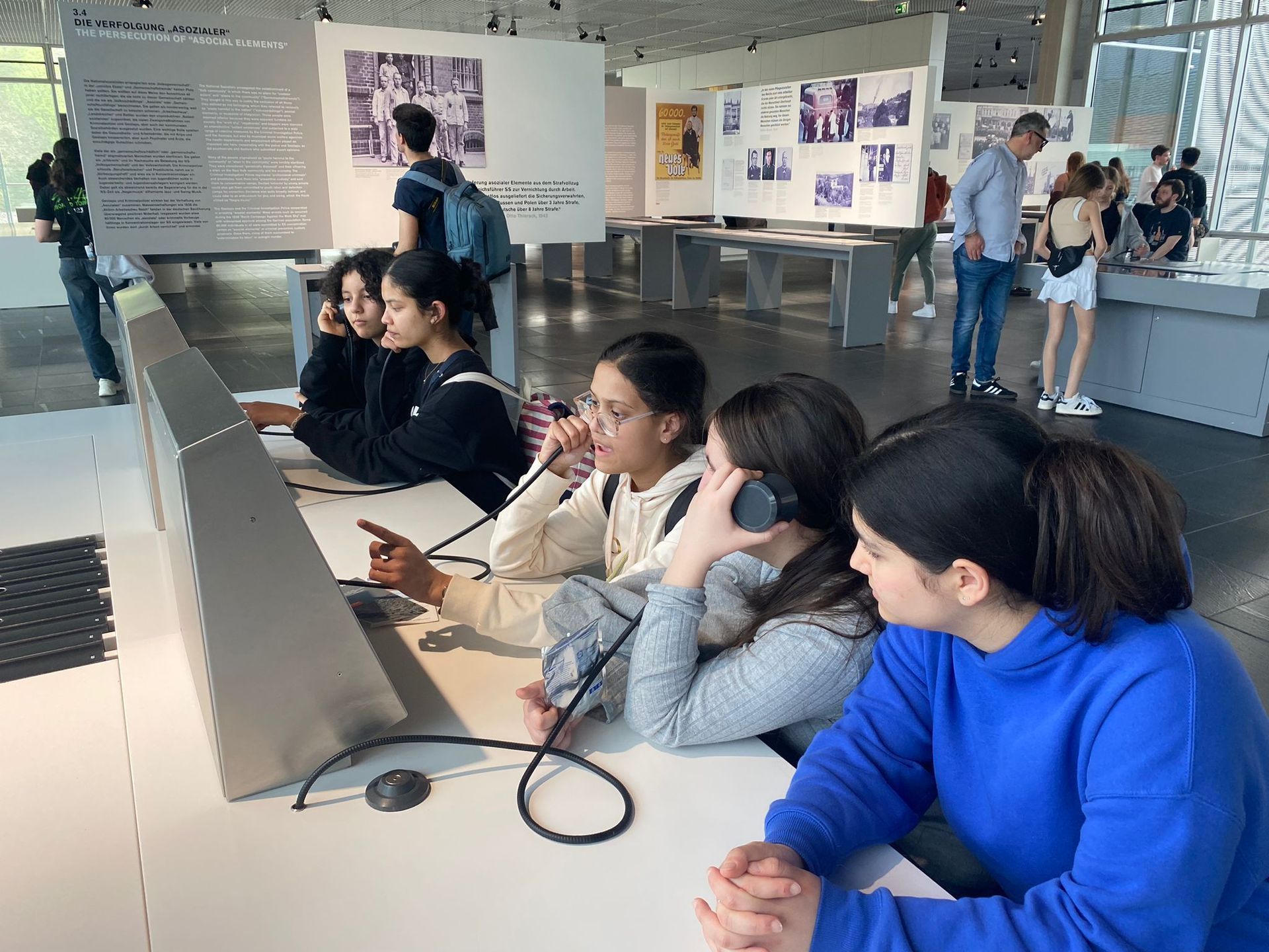 Jugendliche, die in einem Klassenzimmer oder Labor an Computerarbeitsplätzen Kopfhörer tragen, zusammenarbeiten und Laptops benutzen.