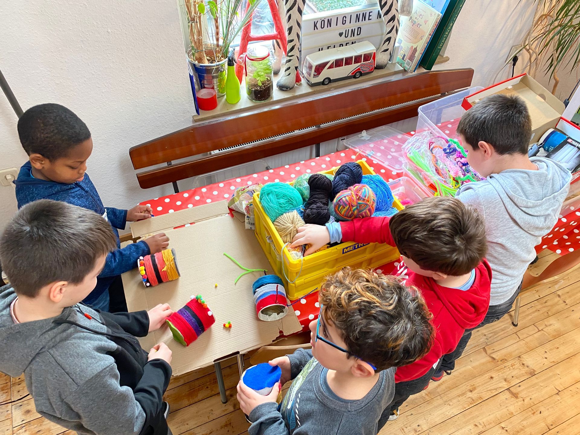 Kinder spielen in einem hellen Klassenzimmer mit bunten Bauklötzen um einen Tisch herum.