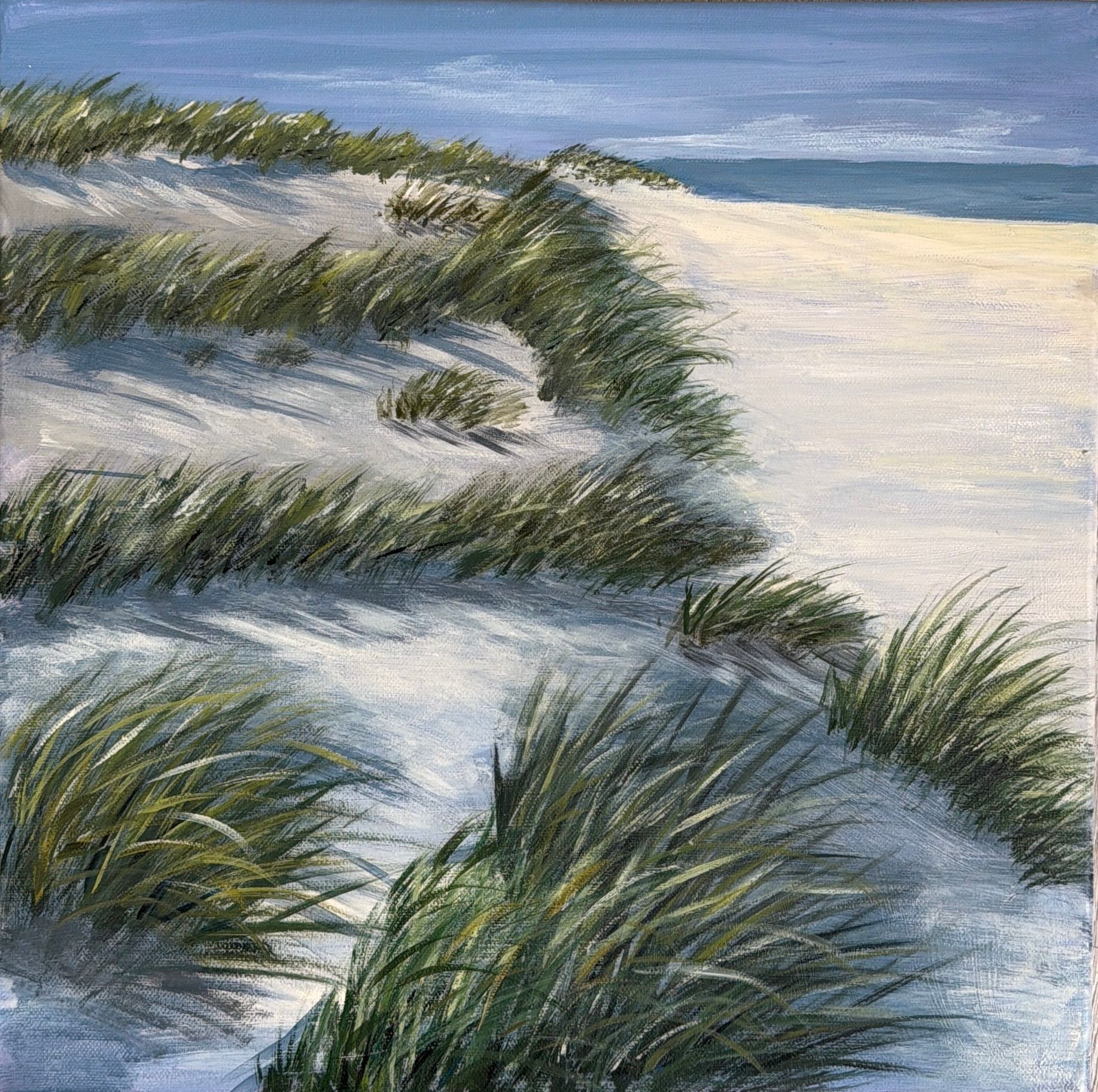 Grasbewachsene Sanddünen neben einem ruhigen blauen Ozean unter einem hellen Himmel