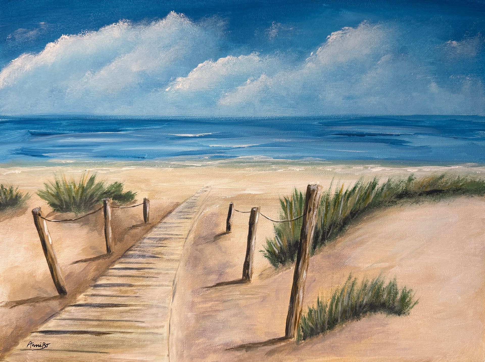Sandstrand mit Holzsteg und Dünen, die zu einem blauen Ozean unter bewölktem Himmel führen