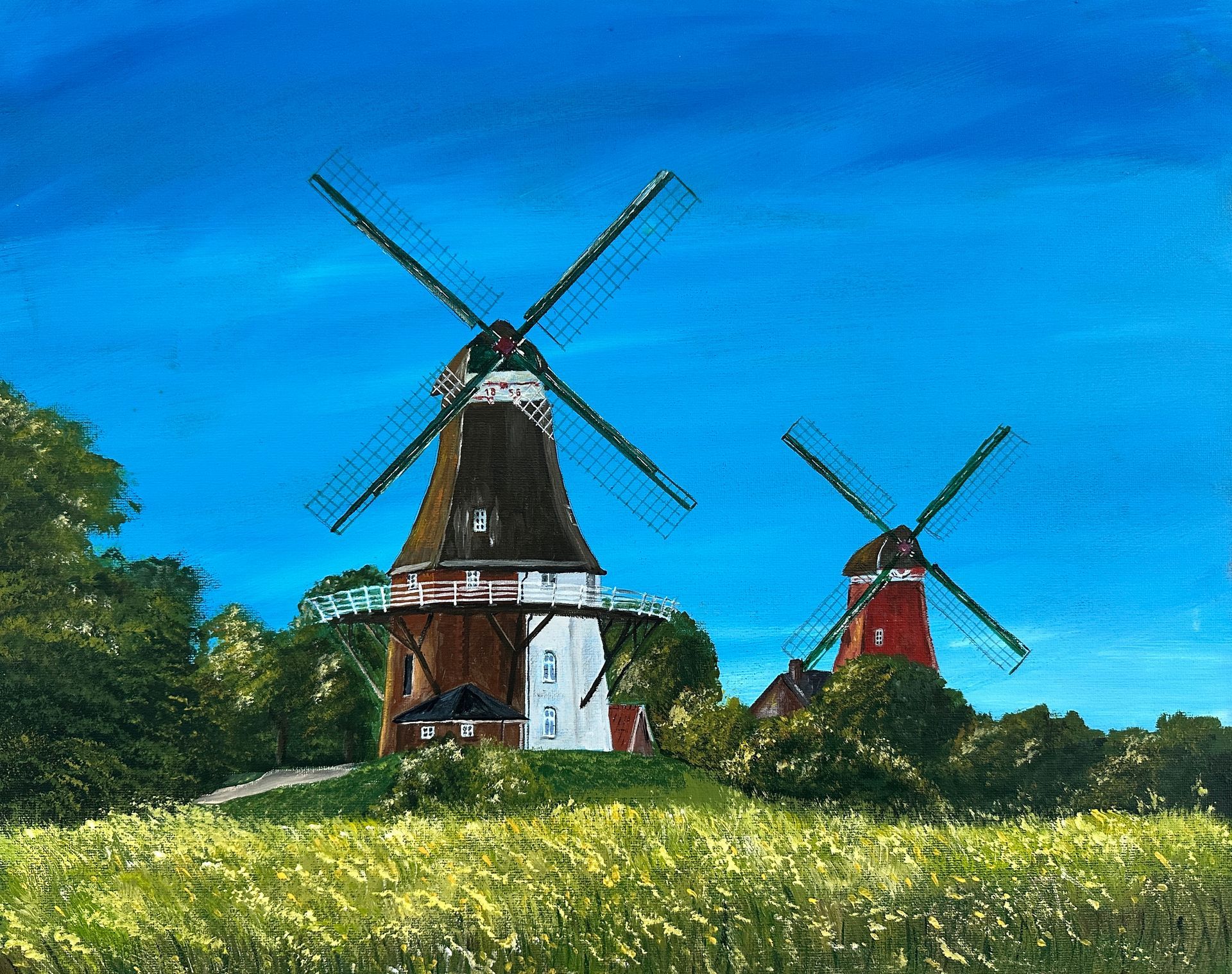 Zwei Windmühlen in Greetsiel auf einem sonnigen Feld unter strahlend blauem Himmel, eine schwarz-weiß und eine rot