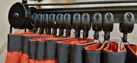 Schwarze Gardinenschiene mit darunter hängenden, rot gefütterten schwarzen Gardinen.