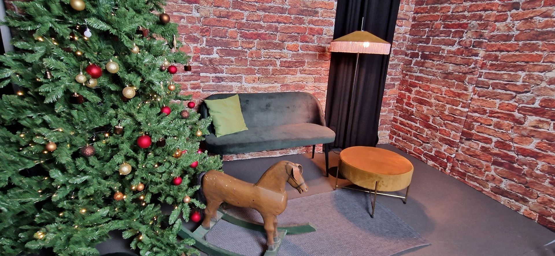 SchaukelpferdWeihnachtsszene mit Baum, Sofa, Ziegelmauer, Pferdestatue und Ottomane.