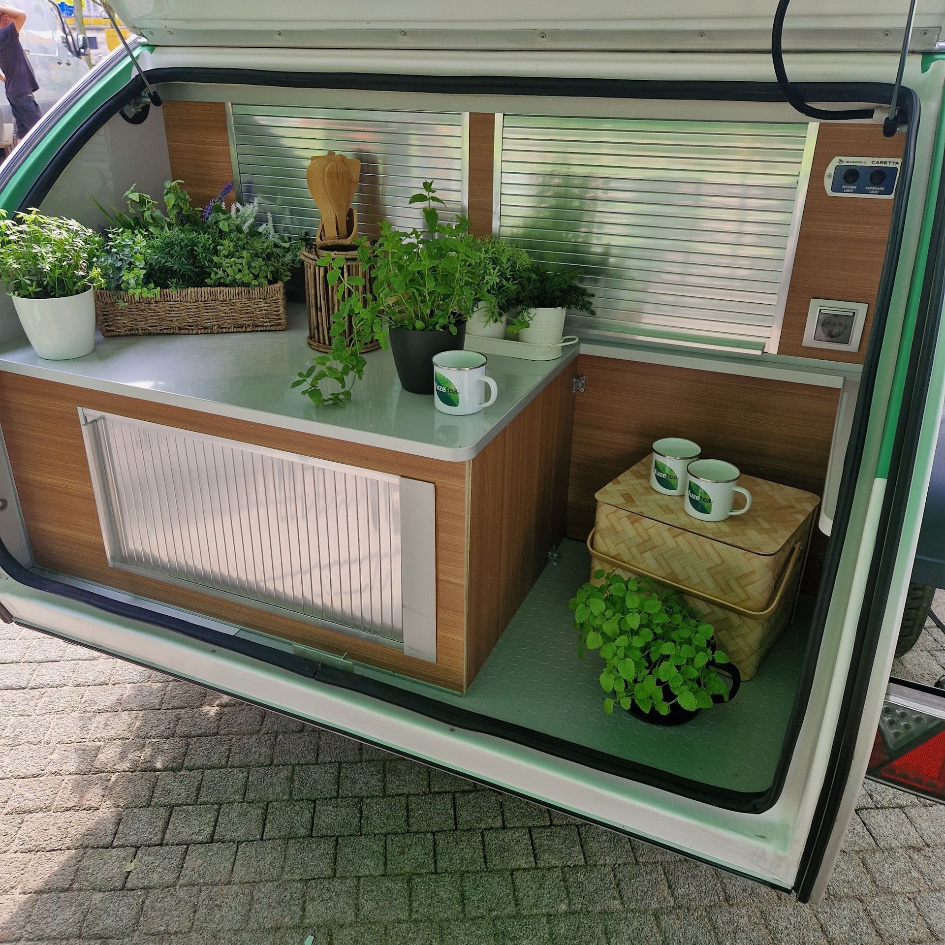 Innenraum eines tropfenförmigen Wohnmobils mit Pflanzen, einer Arbeitsfläche und einer Aufbewahrungsbox.