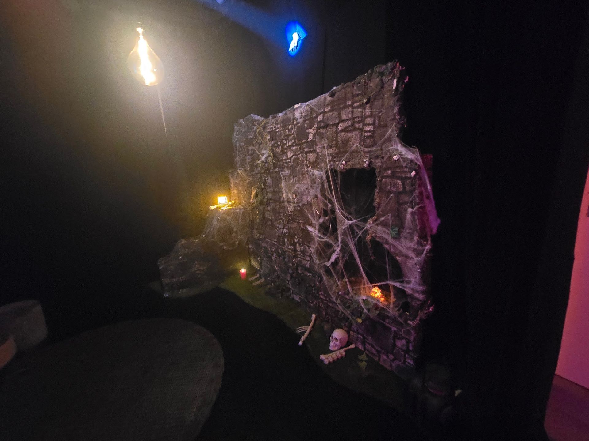 Gruselige Burgfassade mit Spinnweben, beleuchtet von orangefarbenen und blauen Lichtern. Inklusive Totenköpfen und Kerzen.