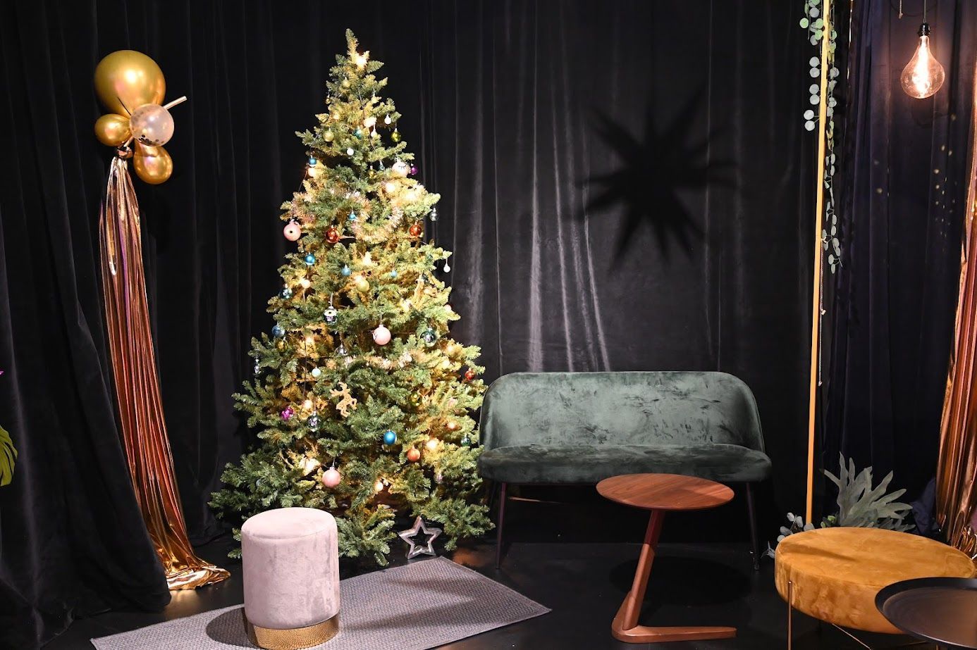 Weihnachtszimmer mit Baum, Samtsofa, runden Tischen, schwarzen Vorhängen, goldenen Akzenten und einem Sternenschatten.