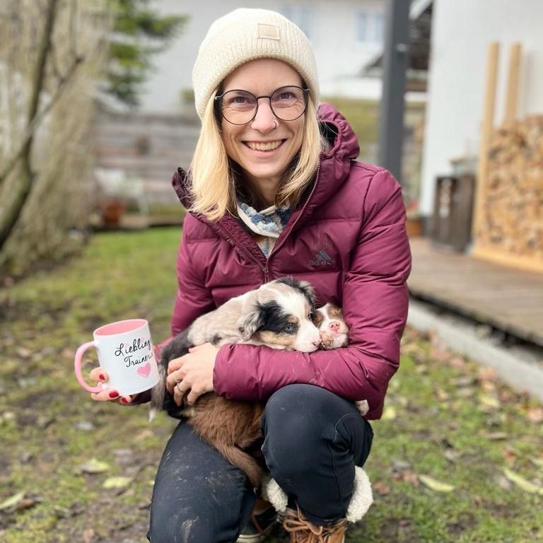 Hundewelpe auf dem Schoß mit Kaffeetasse in der Hand