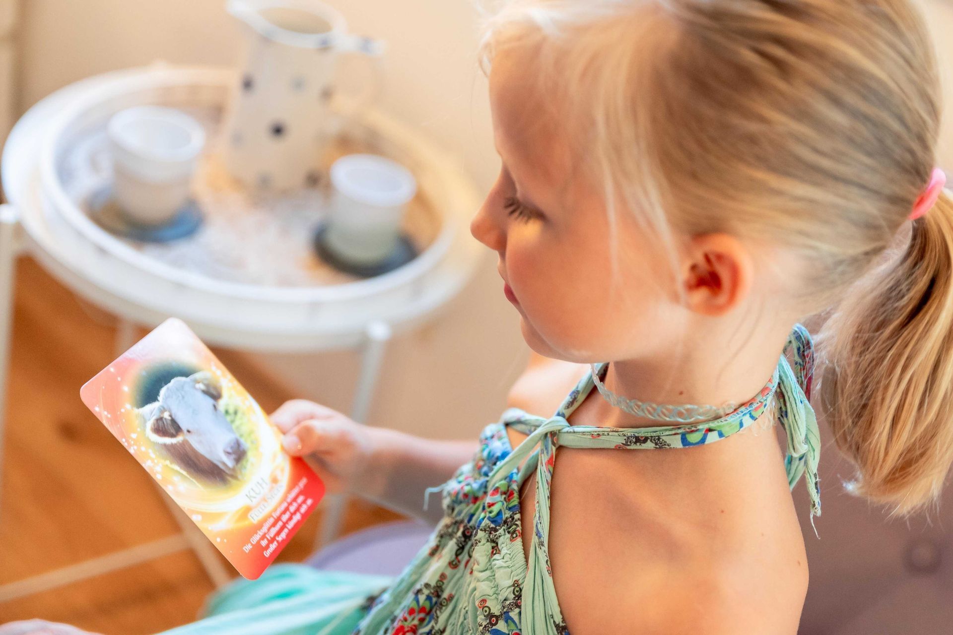 Kind im grünen Kleid betrachtet bunte Karte mit Kuhkopf, während der Behandlung 