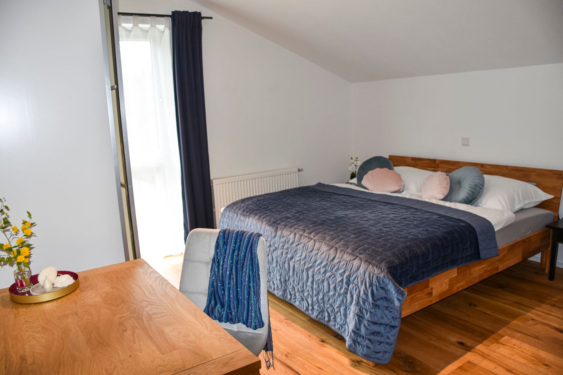 Gemütliches Doppelbett aus Massivholz im hellen Schlafzimmer des Apartments Auszeit.