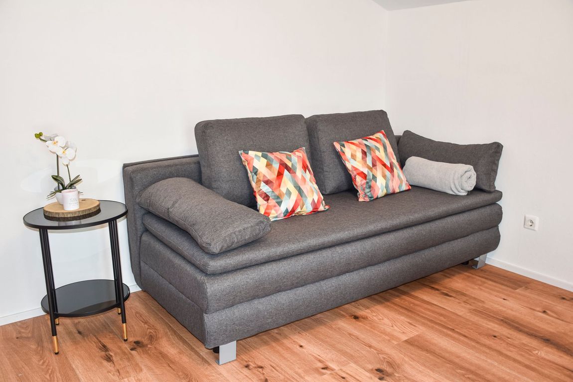 Gemütliches Sofa im offen gestalteten Wohn- und Esszimmer des Apartments Auszeit – flexibel nutzbar als Couch oder zusätzlicher Schlafplatz.