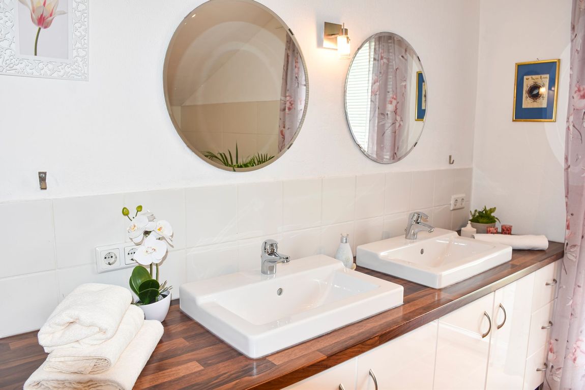 Stilvolles Doppelwaschbecken mit zwei großen Spiegel im hellen und komfortabel eingerichteten Bad der Ferienwohnung Auszeit.