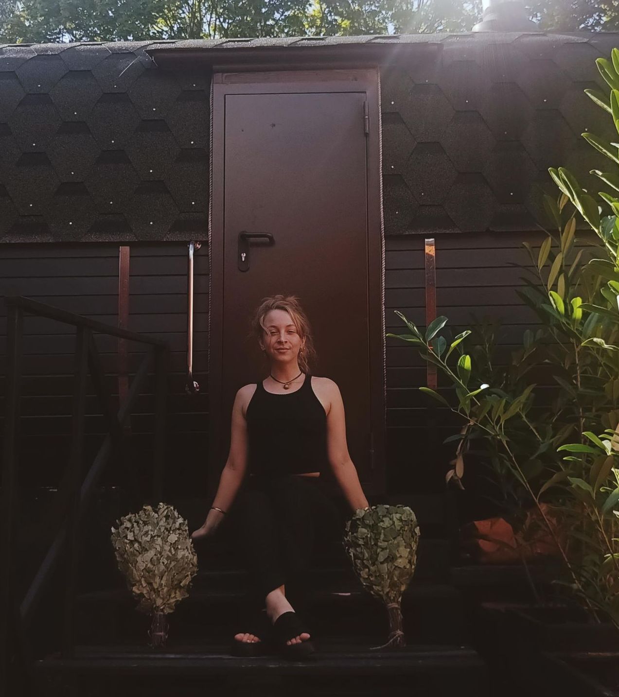 woman in front of sauna with birch branches 