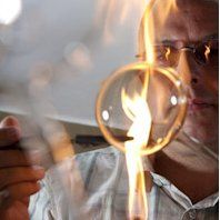 Uwe Bäz bei der Arbeit vor der Flamme, er stellt gerade ein Windlicht her.