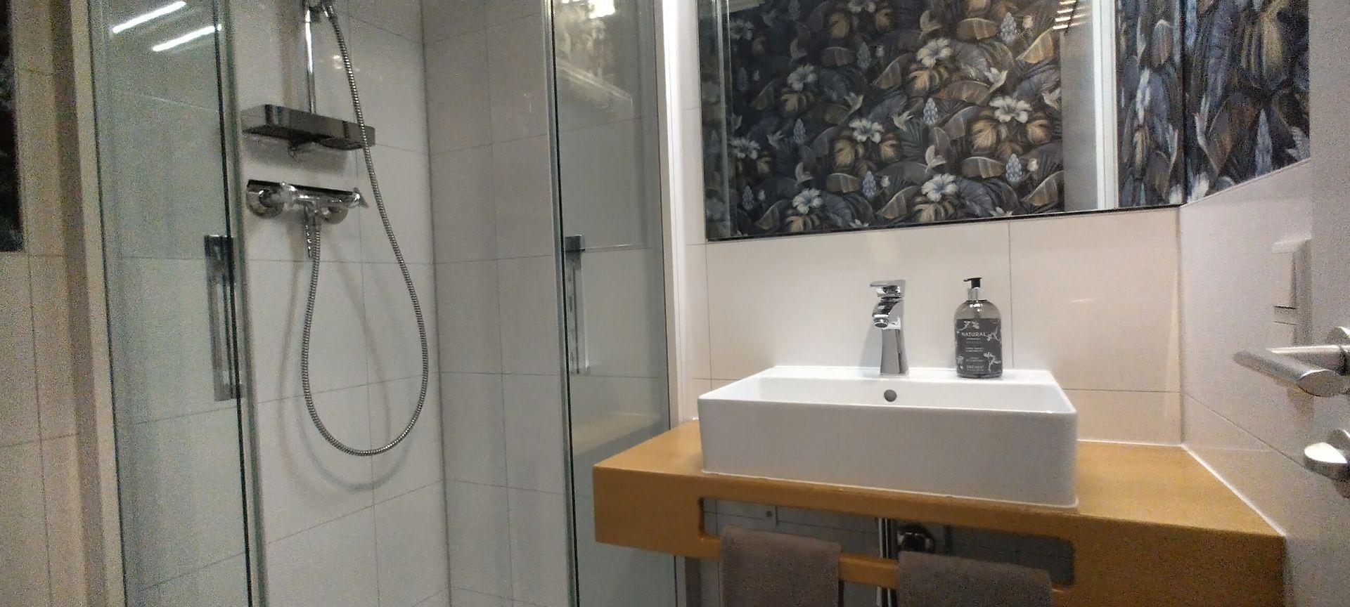 Stilvolles Badezimmer – mit Dusche, Waschbecken und freundlicher Ausstattung.